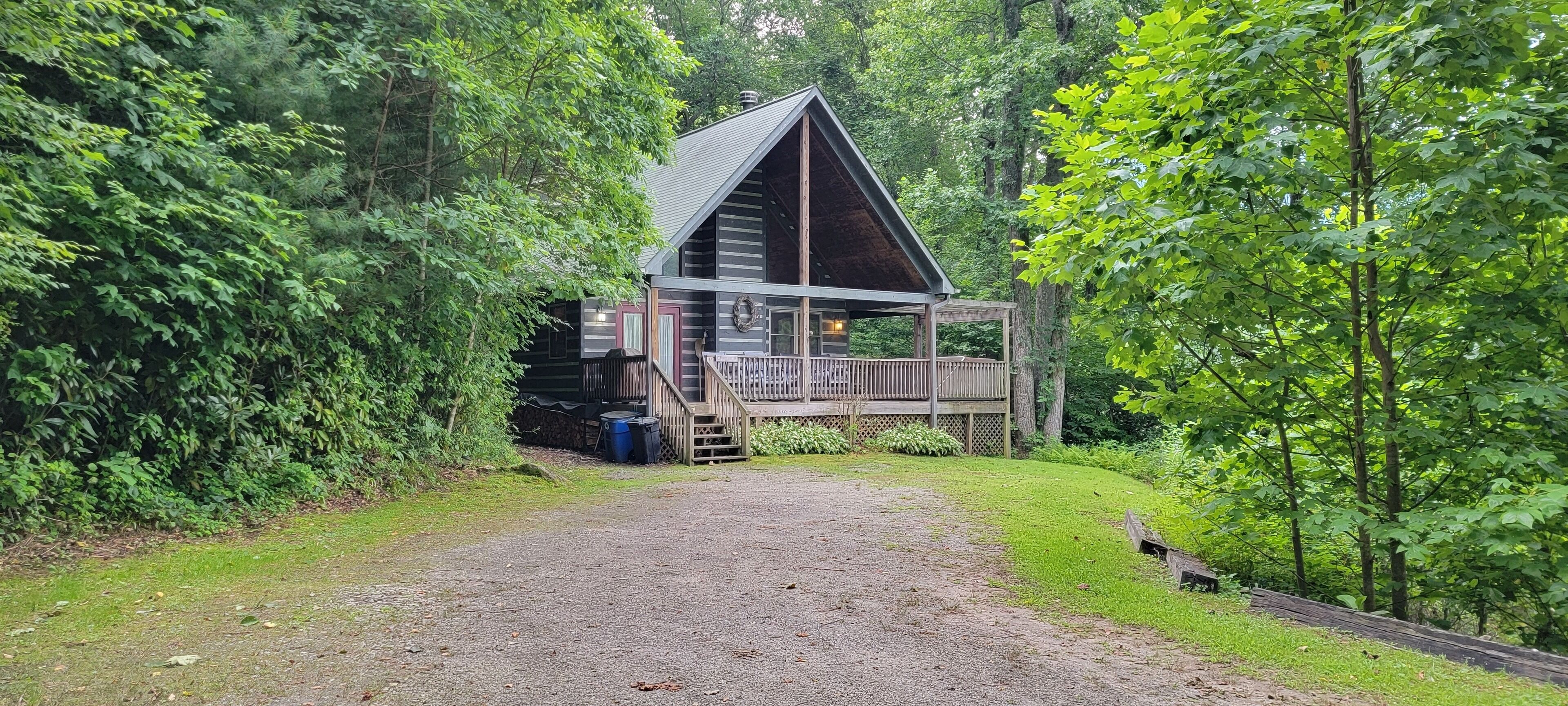Une cabane dotée d’une terrasse en bois et d’un porche, entourée d’un feuillage verdoyant et luxuriant.