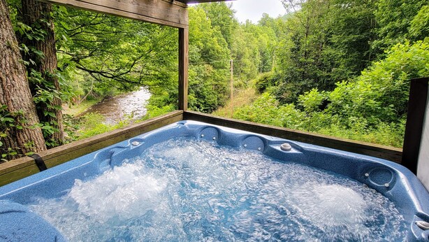 A hot tub with a view of a forested area through a wooden window frame. - Hot Tub, River Views, Couples & Families!!! (Burnsville)