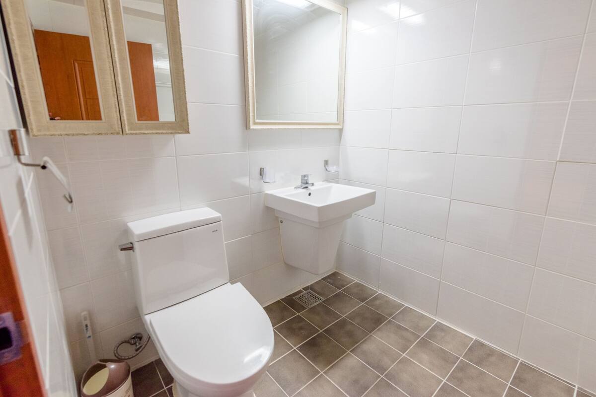 A small, clean bathroom with a toilet, sink, and two mirrors.