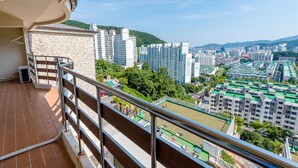 A balcony with a view of a cityscape, including high-rise buildings and a green park area.