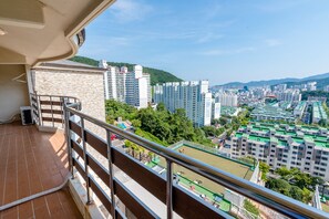 A balcony with a view of a cityscape, including high-rise buildings and a green park area.
