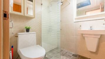 A bathroom with a toilet, a glass shower enclosure, a sink, and a mirror.