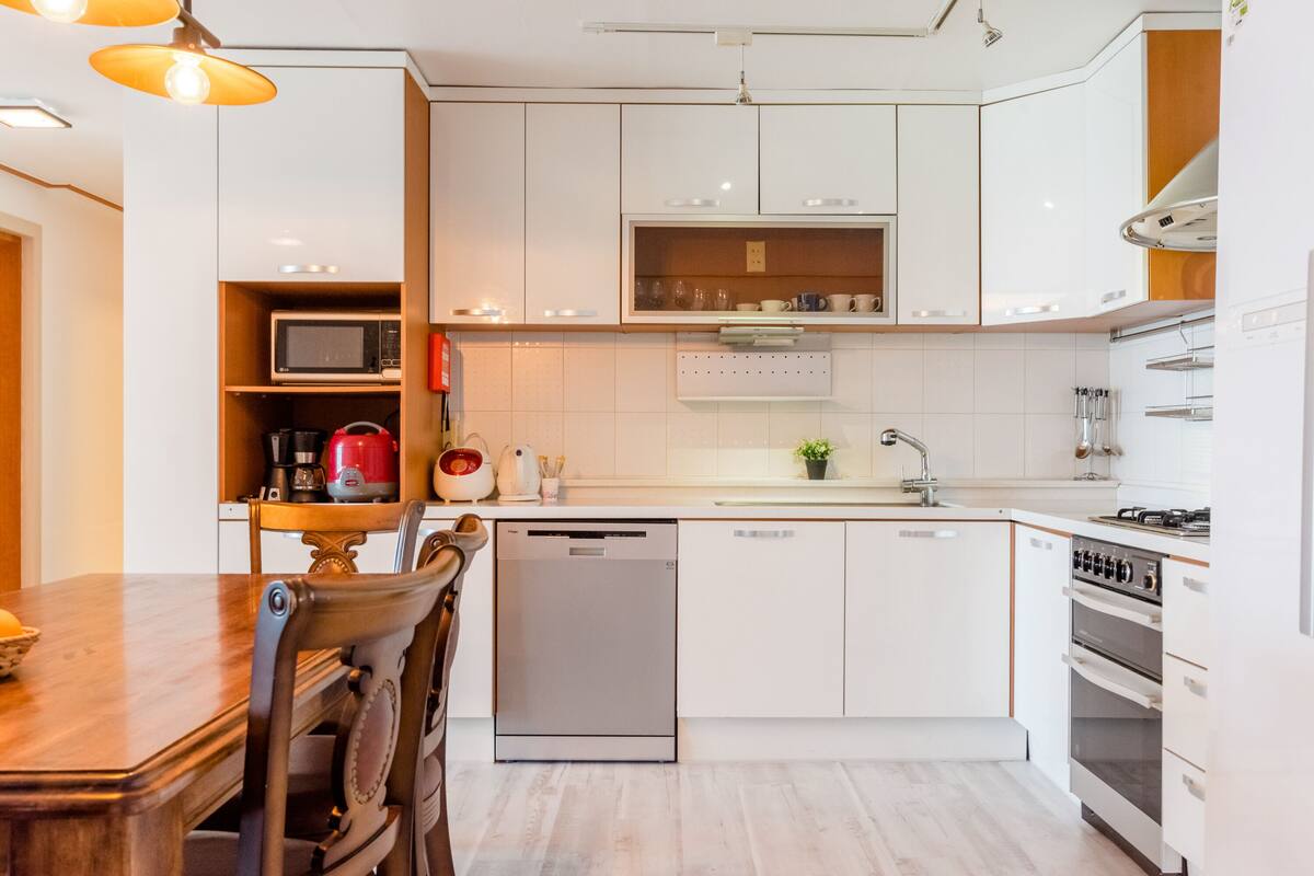 A modern kitchen with white cabinets, a dishwasher, a stove, and a microwave.