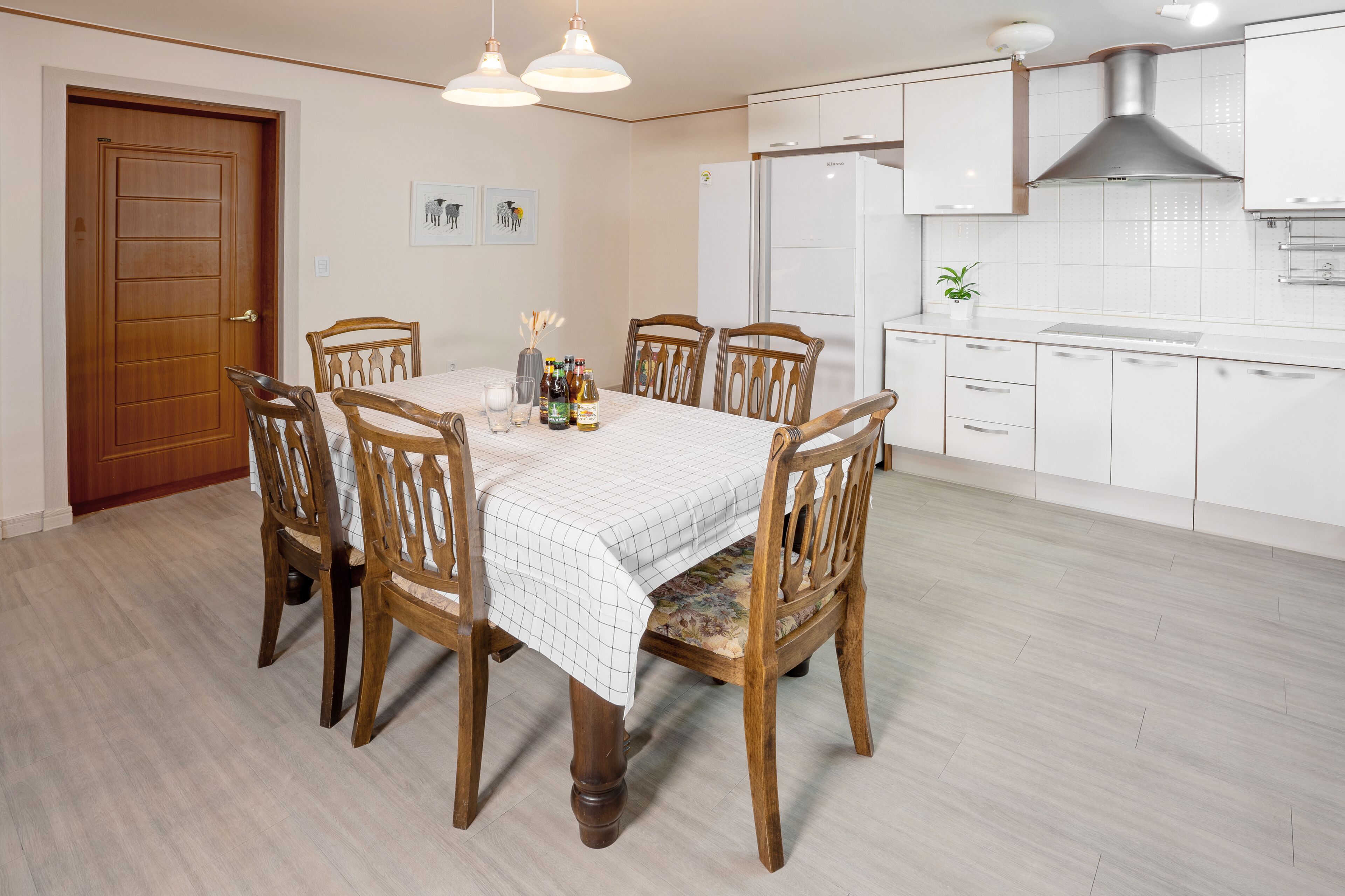 Comedor con mesa y sillas de madera, salpicadero de azulejos blancos y extractor de acero inoxidable sobre la estufa.