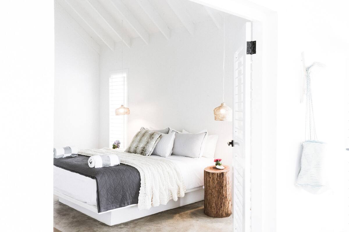Un dormitorio minimalista con cama, mesitas de noche e iluminación colgante.