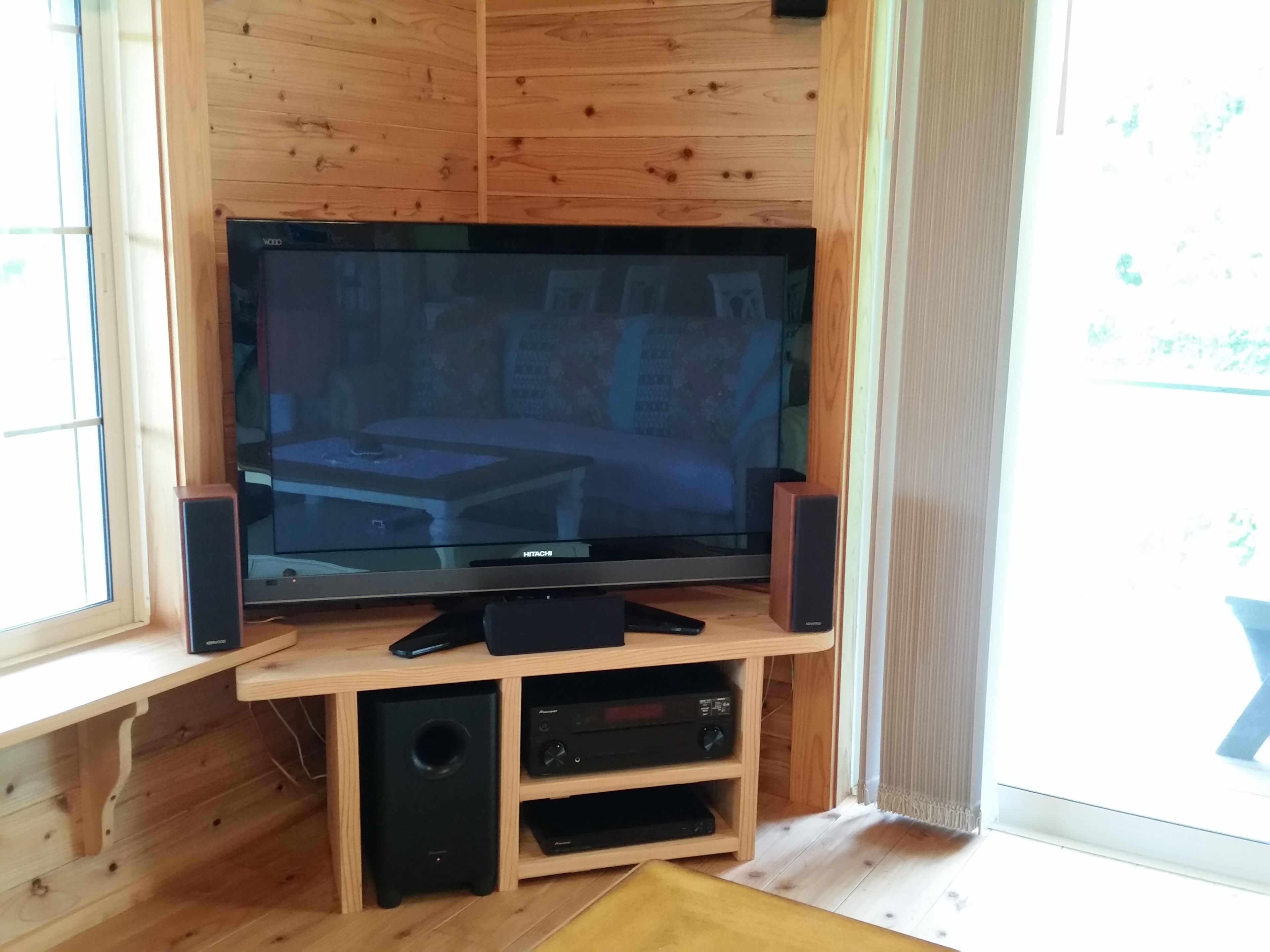 A wooden-paneled room with a flat-screen TV on a wooden stand, two speakers, and a small shelf below the TV.