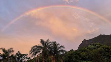 A mountain landscape with a rainbow arching over a forested area.