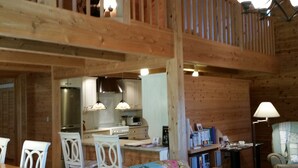 A cozy cabin interior with a dining area, kitchen, and a loft space. - Cottage HANA MANA (Yakushima)