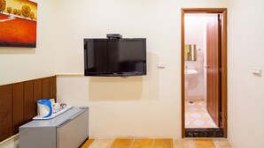 A small room with a flat-screen TV mounted on the wall, a small desk with a kettle, and a tiled floor. - Mong Shan Homestay (Hengchun)