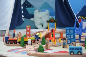 Um conjunto de trens de brinquedo com diversos veículos e edifícios, incluindo uma figura de policial e um ônibus.