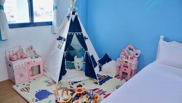Een kinderkamer met een tent, een roze keukentje en een bed.