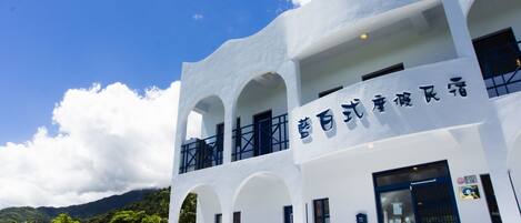 Un edificio blanco con detalles azules y un letrero en un idioma extranjero.