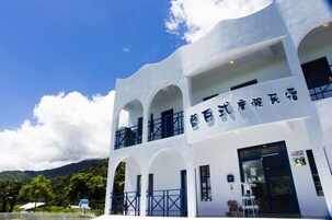 Um edifício branco com detalhes em azul e uma placa em idioma estrangeiro.