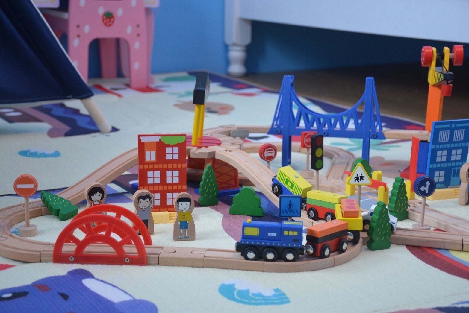 A toy train set with buildings, trees, and traffic signs.