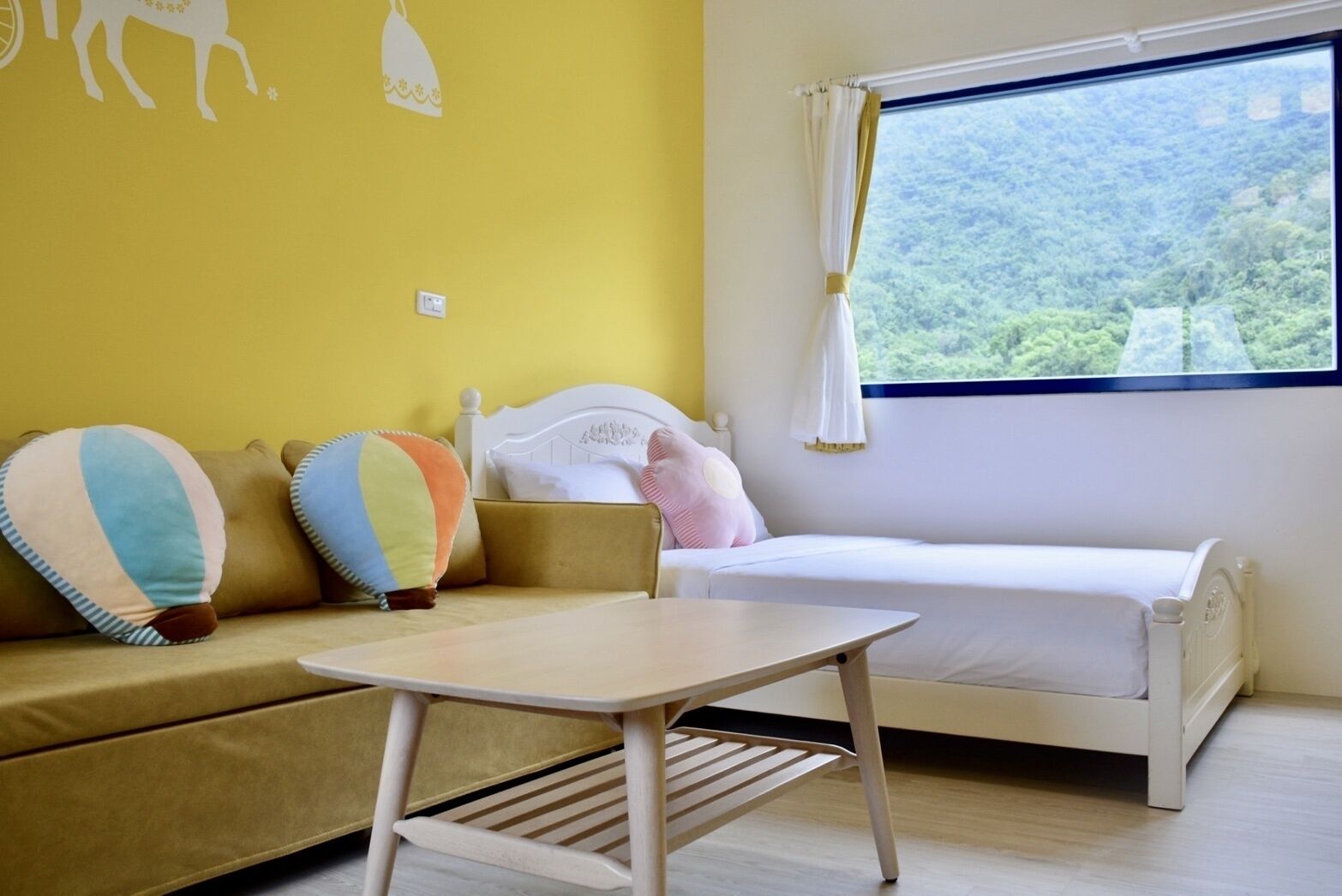 Una habitación con una cama, una mesita y un sofá con almohadas de colores.