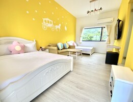 Quarto com cama, mesa de cabeceira e janela com vista para o verde.