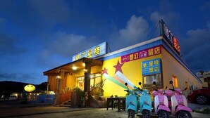 A brightly lit building with a signboard and a scooter parked in front. - Kenting Star Inn (Hengchun)