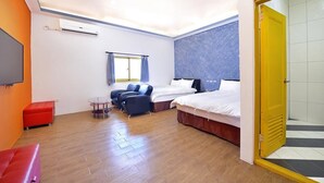A hotel room with two beds, a red sofa, a small table, and a window with curtains. - Kenting Star Inn (Hengchun)