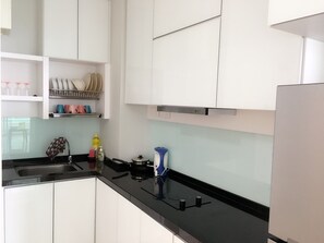 A kitchen with white cabinets, a black countertop, and a stainless steel range hood. - Mansion Deluxe and Double Seaview Suite (George Town)