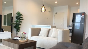 Un salon moderne avec un canapé, une table basse, une plante en pot et un réfrigérateur.