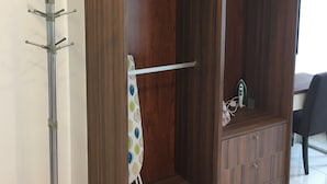 Une armoire en bois, dotée de plusieurs compartiments, et un porte-manteau en métal placé à côté.