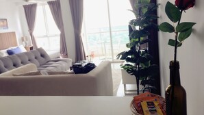 Un salon avec un canapé, une table basse, une rose et une plante dans une bouteille.