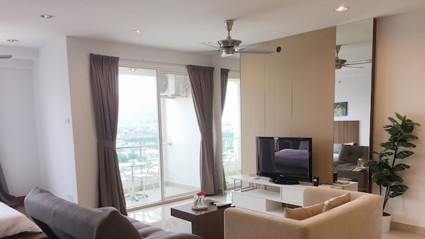Un salon moderne avec un canapé, un téléviseur et un balcon agrémenté de rideaux.