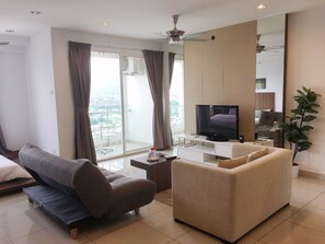 Uma sala de estar moderna com sofá, televisão e varanda com cortinas.