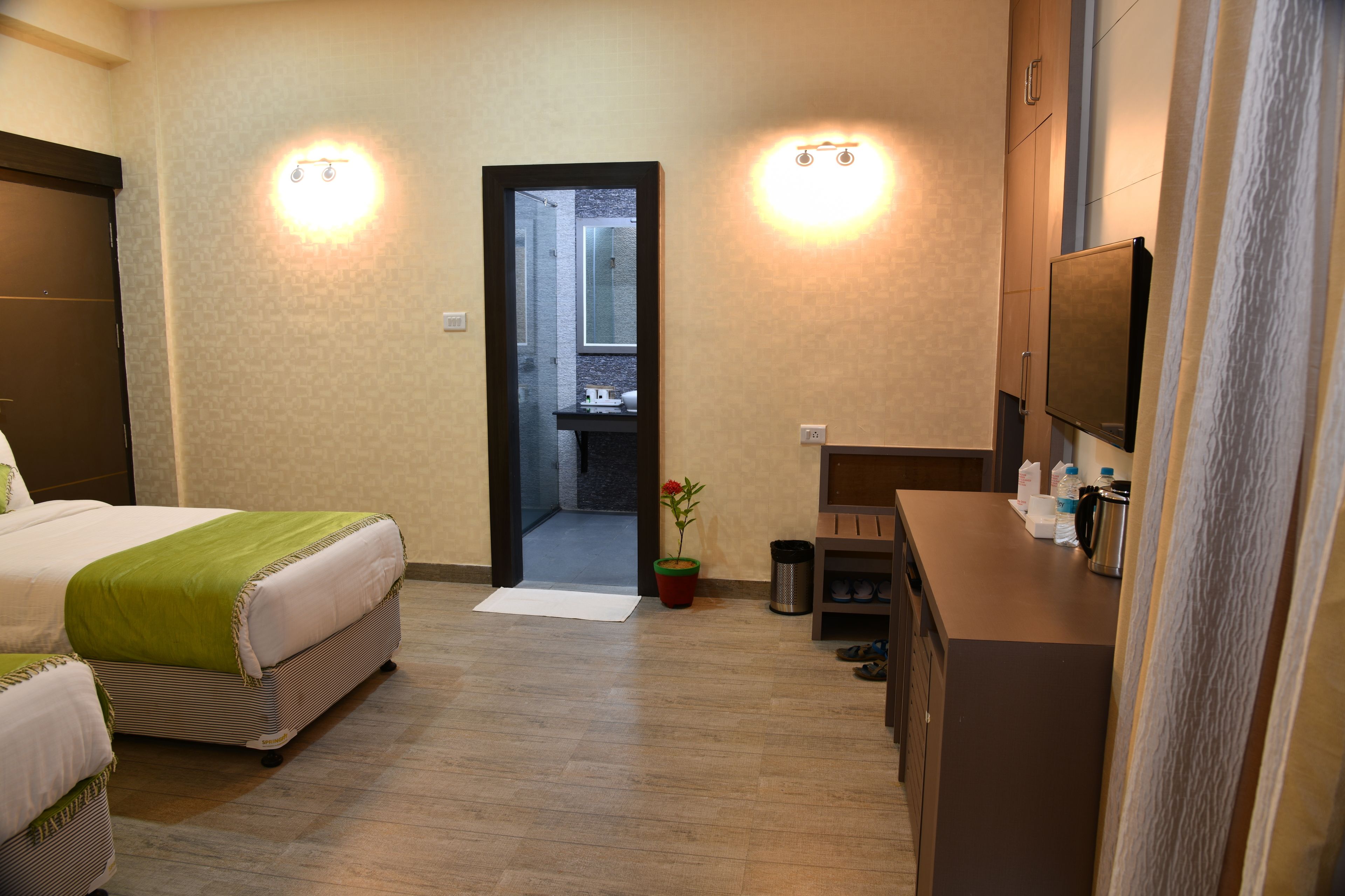 Una habitación de hotel con cama, escritorio, espejo y puerta que da a un baño.