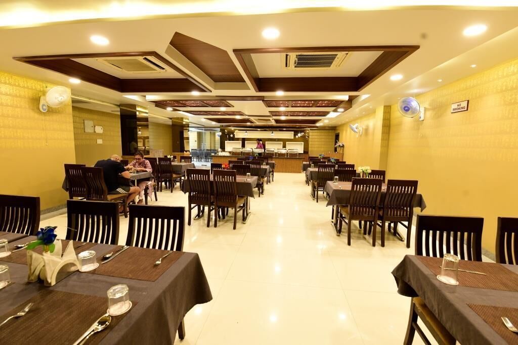 Un restaurant amb diverses taules i cadires, una zona de mostrador i ventiladors de sostre.