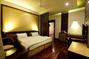 Una habitación de hotel con cama, escritorio, silla, mesita y televisión.