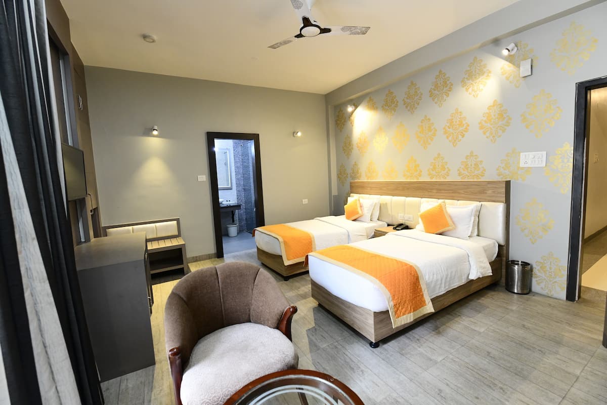 A hotel room with two beds, a chair, a desk, and a television.