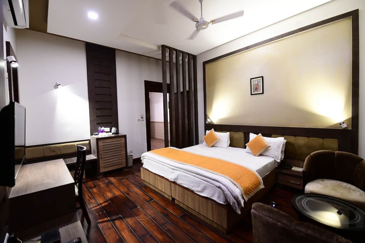 A hotel room with a bed, a desk, a chair, and a ceiling fan.