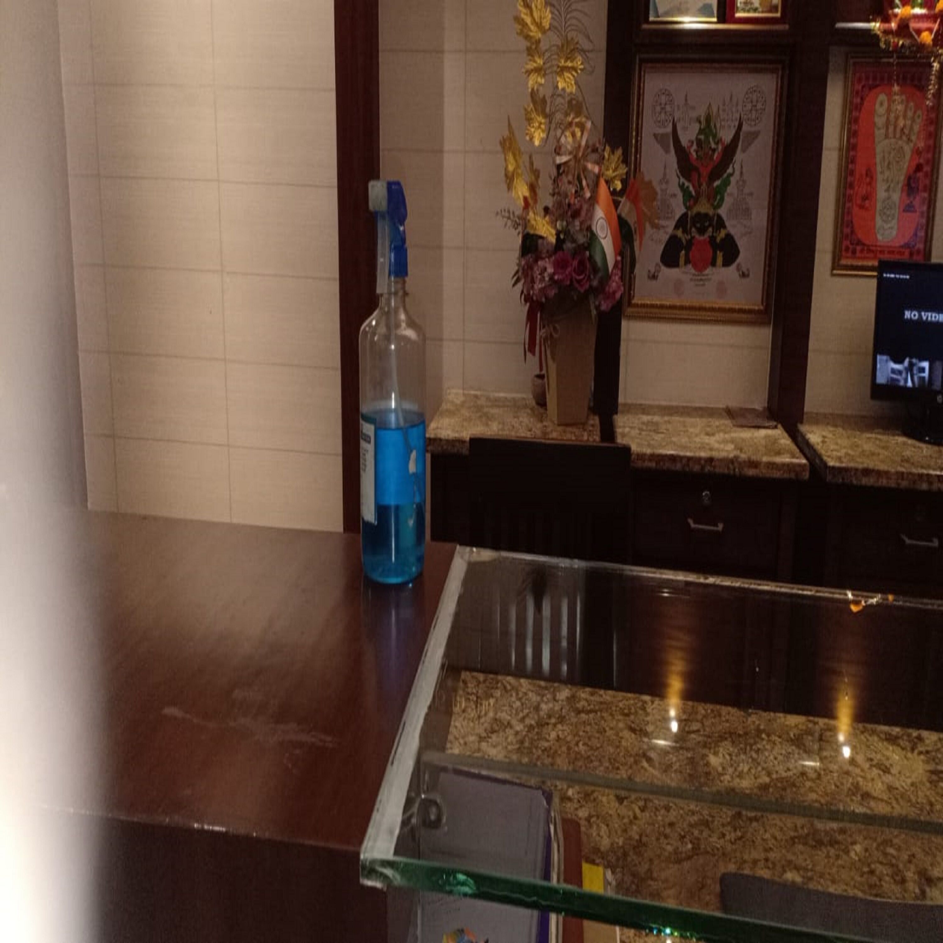 Un espace d’accueil d’hôtel avec une vitrine, une bouteille contenant un liquide bleu et un tableau encadré accroché au mur.