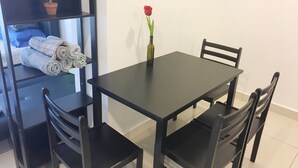 A dining area with a table and four chairs, a small potted plant, and a rolled towel on a shelf. - Mansion One Bedroom Suite (George Town)