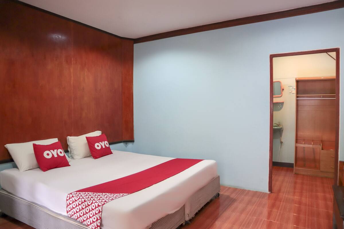 A hotel room with a bed, wooden headboard, and a wardrobe.
