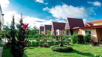 A row of houses with red roofs and a well-maintained garden with a birdbath and various plants.