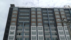 Een hoog gebouw met meerdere verdiepingen, uitgevoerd in een modern architectonisch ontwerp met diverse raamstijlen en balkons.
