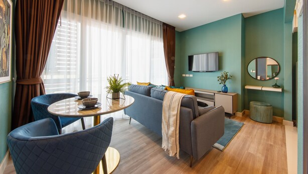Een moderne woonkamer met een bank, stoelen, een televisie en een eethoek met een tafel en stoelen.