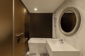 Ein modernes Badezimmer mit einer Badewanne, einem Waschbecken und einem großen Spiegel.