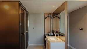 A modern bathroom with a large mirror, a sink, and a walk-in closet.