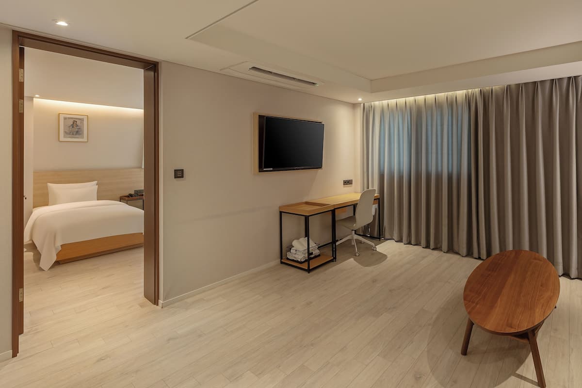 A hotel room with a bed, a desk, a chair, a television, and a large window with curtains.