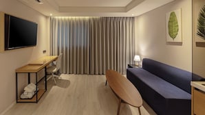 A modern living room with a flat-screen TV, a wooden desk, a blue sofa, and a bench.