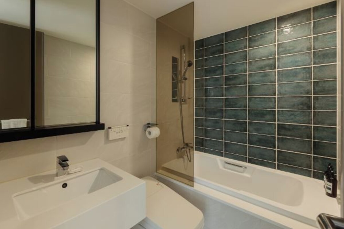 Un baño con lavamanos blanco, espejo, ducha y bañera.