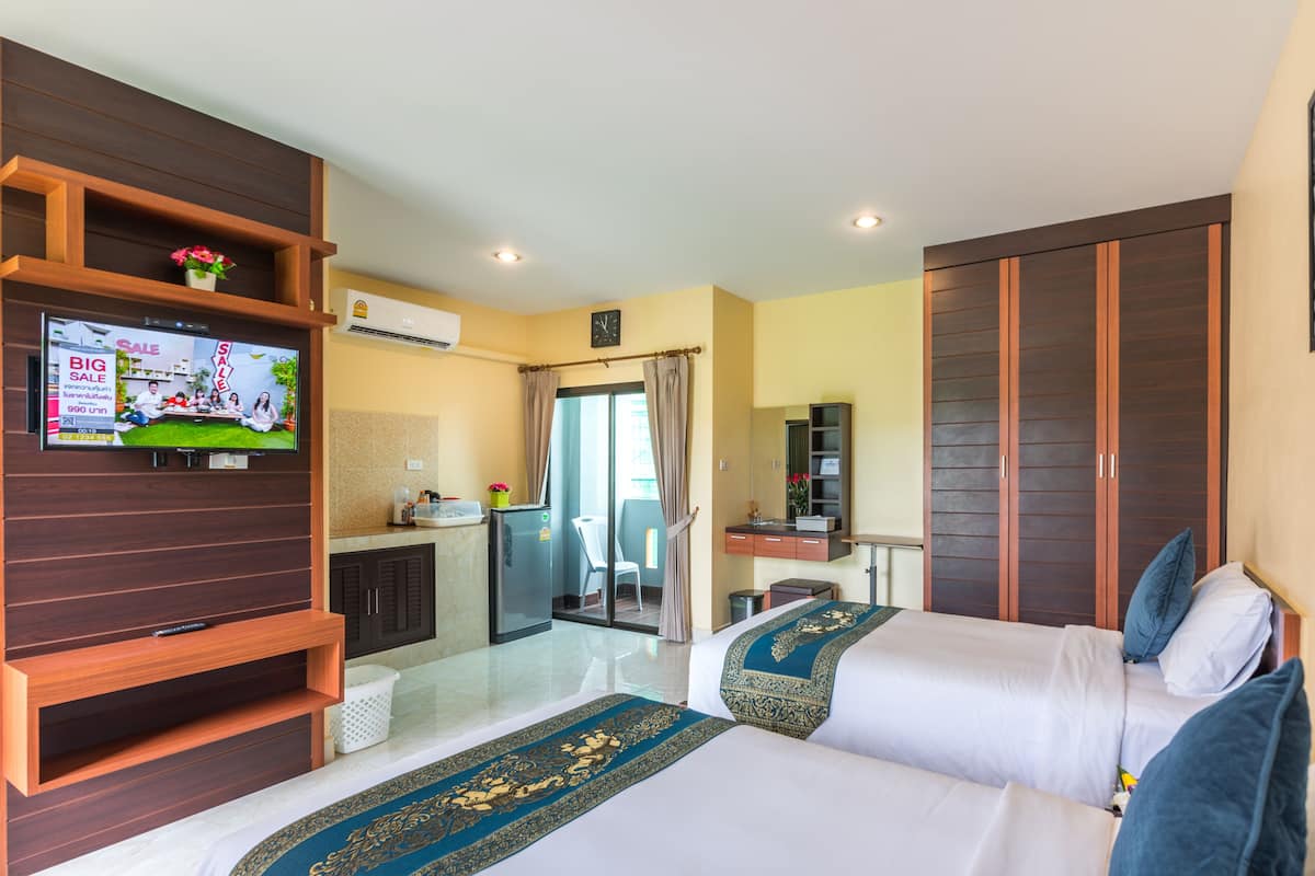 A hotel room with two beds, a TV, a desk, a mirror, and a wardrobe.