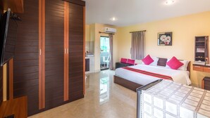 Une chambre d’hôtel avec un grand lit, une armoire, une télévision et une salle de bain visible à travers une porte ouverte.