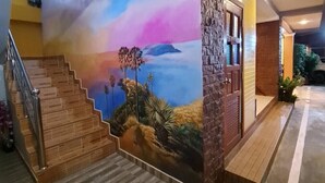 Un escalier menant à une sortie de secours, une fresque représentant un paysage et une horloge au mur.