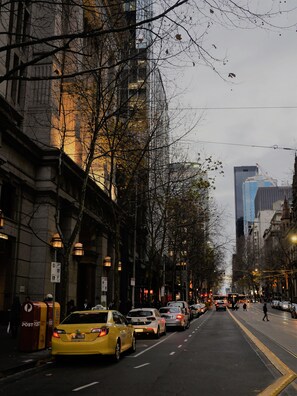 A city street lined with tall buildings, a taxi, and parked cars. - Corporate Stayz at Collins (Melbourne)