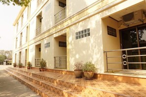 A building with a tiled entrance, potted plants, and a metal railing. - Phimaibury Apartment (Phimai)