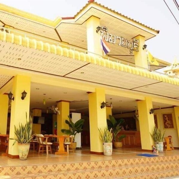 A building with a yellow facade and a sign in a foreign script. - Phimaibury Apartment (Phimai)
